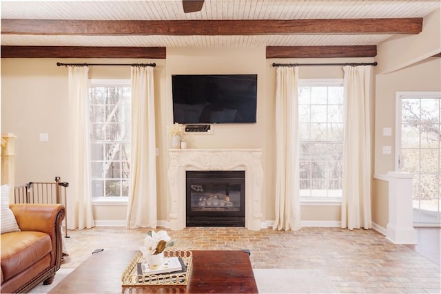 living room featuring beam ceiling, wood ceiling, a high end fireplace, and plenty of natural light