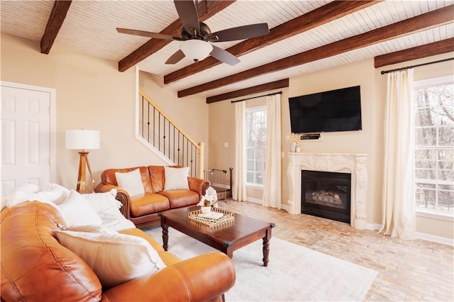 living room featuring wood ceiling, beam ceiling, a fireplace, and ceiling fan