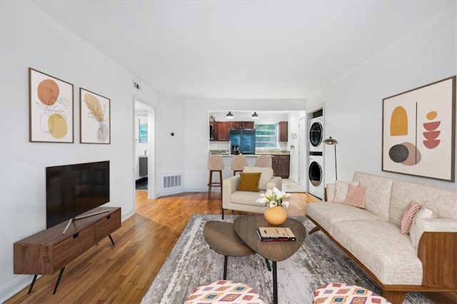 living room featuring hardwood / wood-style floors and stacked washer and clothes dryer