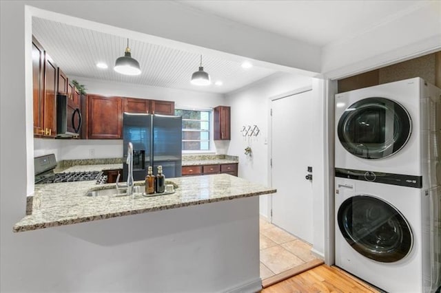 washroom featuring stacked washer / dryer, sink, and light wood-type flooring