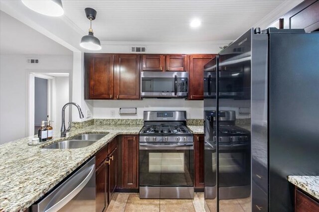 kitchen with pendant lighting, sink, light stone countertops, light tile patterned flooring, and stainless steel appliances