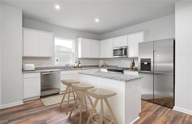 kitchen with dark hardwood / wood-style floors, white cabinetry, appliances with stainless steel finishes, and a center island