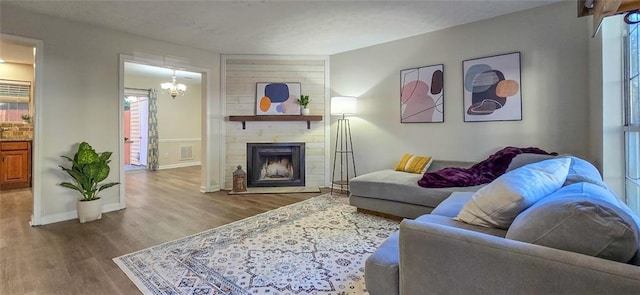 living room with a large fireplace, hardwood / wood-style flooring, and a notable chandelier