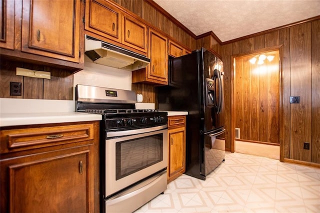 kitchen with wooden walls, ornamental molding, stainless steel range with gas stovetop, and a textured ceiling