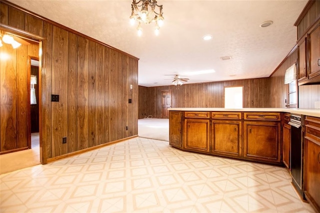 kitchen featuring ceiling fan with notable chandelier, wooden walls, and a textured ceiling