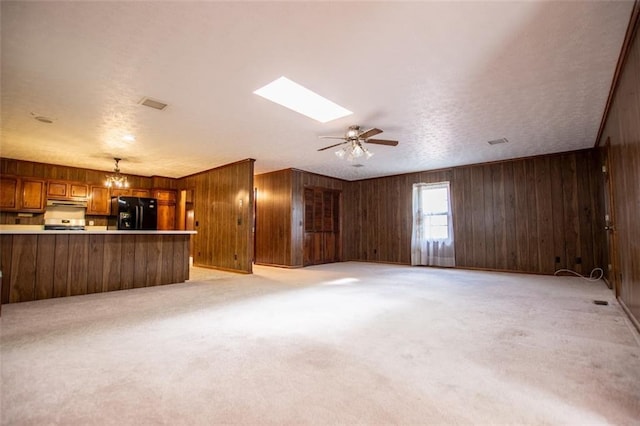 unfurnished living room featuring ceiling fan, a skylight, light carpet, and a textured ceiling