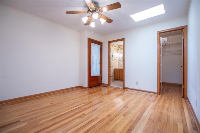 unfurnished bedroom with ceiling fan, connected bathroom, light hardwood / wood-style floors, a walk in closet, and a closet