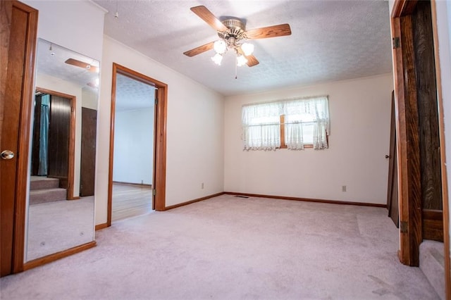 unfurnished bedroom featuring light carpet, a textured ceiling, and ceiling fan