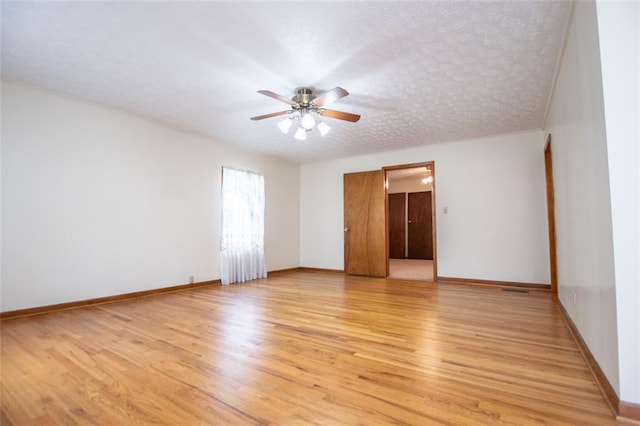 empty room featuring ceiling fan, a textured ceiling, and light wood-type flooring