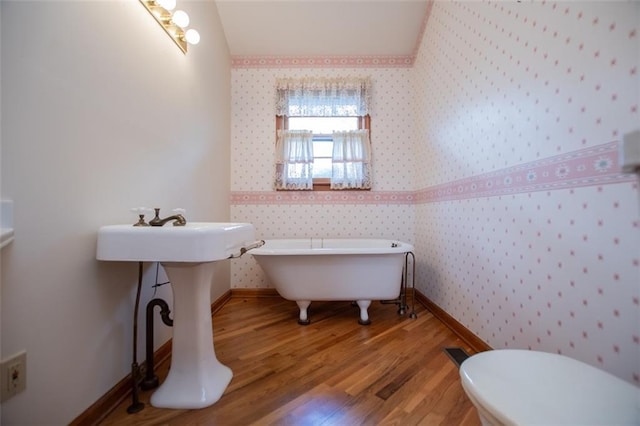 bathroom with a bathtub, hardwood / wood-style flooring, and toilet