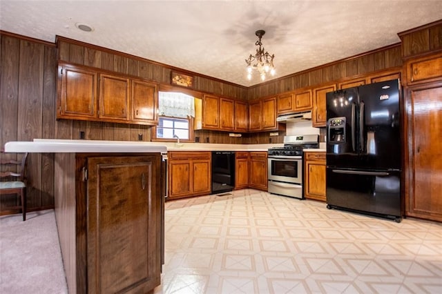 kitchen featuring pendant lighting, wooden walls, a notable chandelier, black appliances, and a textured ceiling