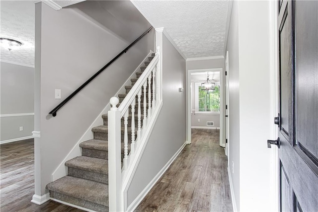 stairs featuring ornamental molding, a textured ceiling, and wood finished floors