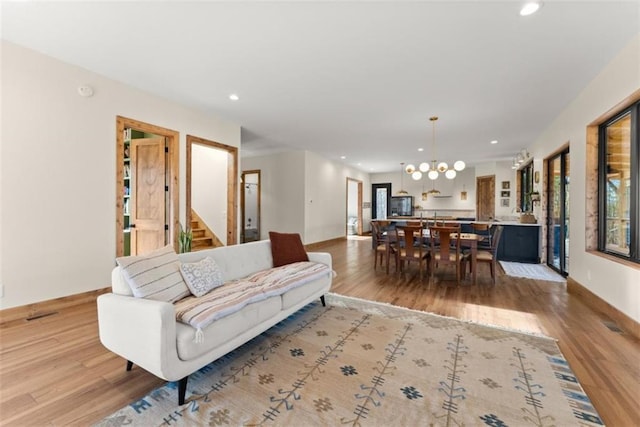 living room featuring an inviting chandelier, plenty of natural light, and light hardwood / wood-style floors