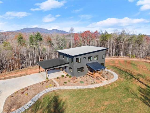 modern home with a front yard, driveway, a view of trees, and a mountain view