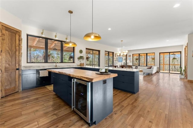 kitchen featuring pendant lighting, light hardwood / wood-style flooring, beverage cooler, and a kitchen island