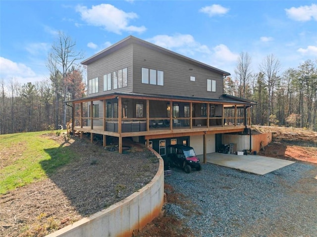 back of property featuring a sunroom, a deck, and a patio area