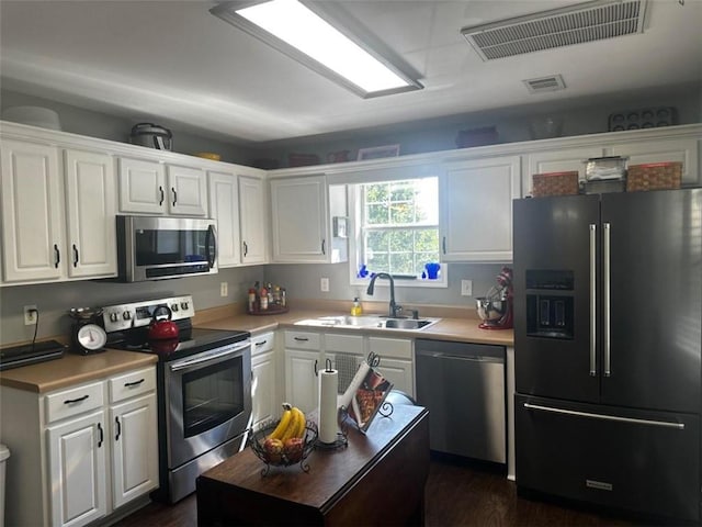 kitchen with appliances with stainless steel finishes, dark hardwood / wood-style flooring, sink, and white cabinets