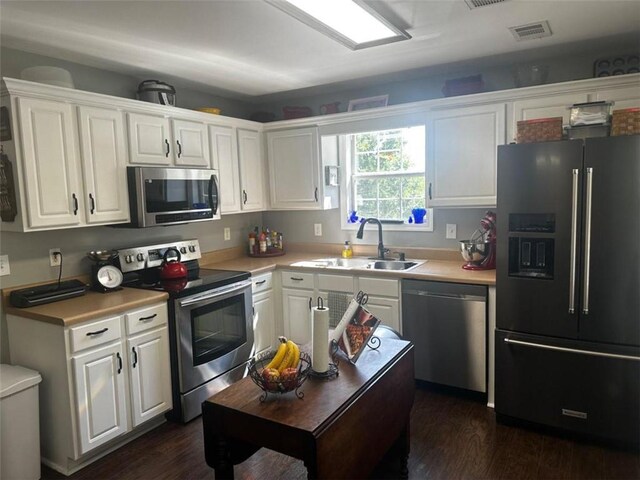 kitchen with appliances with stainless steel finishes, dark hardwood / wood-style flooring, sink, and white cabinets