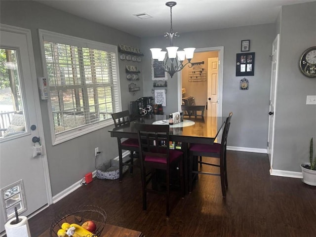 dining area with plenty of natural light, dark hardwood / wood-style flooring, and a chandelier