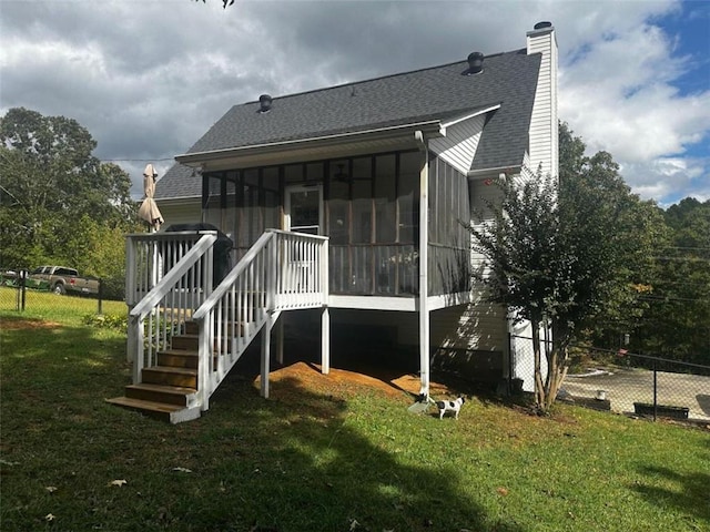 rear view of property featuring a yard and a sunroom