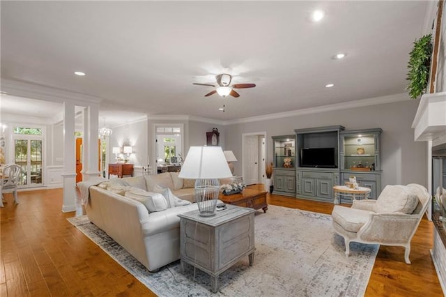 living room featuring ceiling fan with notable chandelier, ornamental molding, a fireplace, and light hardwood / wood-style flooring