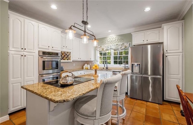 kitchen with light stone counters, stainless steel appliances, decorative light fixtures, white cabinetry, and a kitchen island