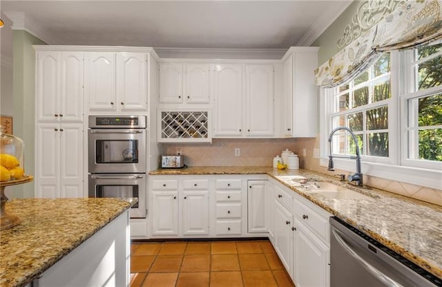 kitchen featuring sink, light stone countertops, light tile patterned floors, white cabinetry, and stainless steel appliances