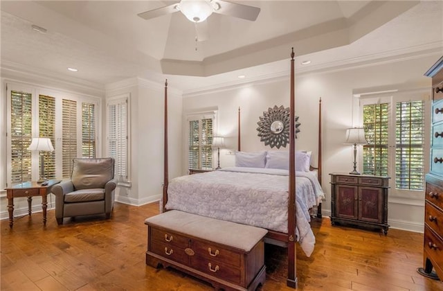 bedroom with hardwood / wood-style flooring, a raised ceiling, ceiling fan, and ornamental molding