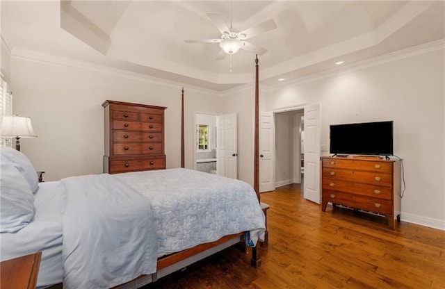 bedroom featuring a raised ceiling, ceiling fan, dark hardwood / wood-style floors, and ornamental molding