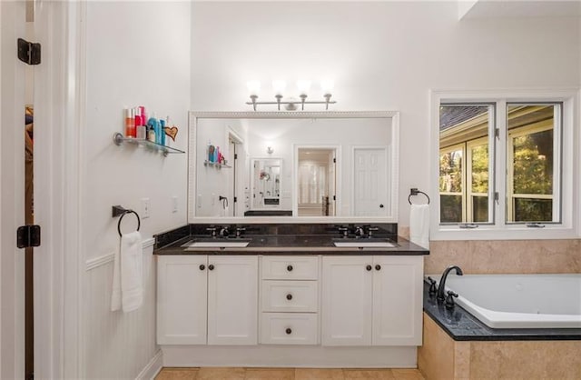 bathroom with tile patterned flooring, vanity, and tiled tub