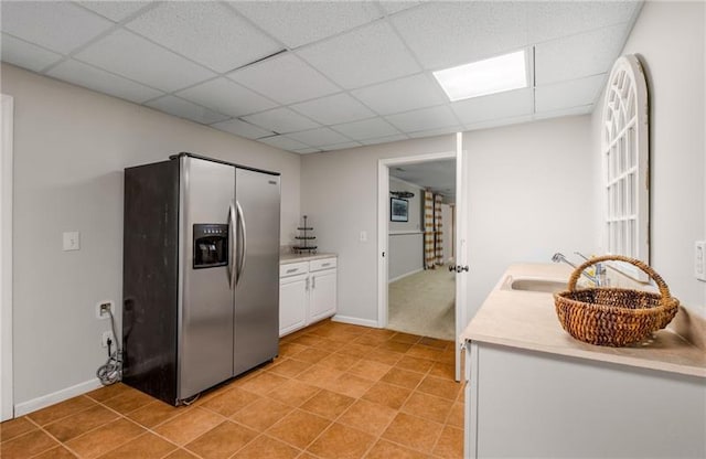 kitchen featuring white cabinets, a drop ceiling, sink, and stainless steel refrigerator with ice dispenser