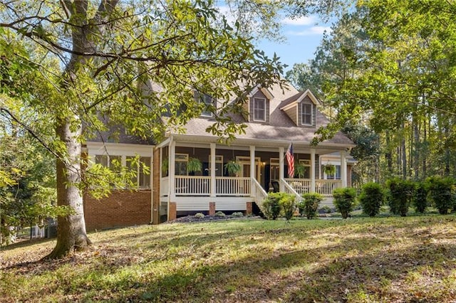 cape cod house with a porch and a front lawn