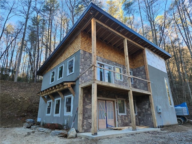 view of front facade featuring stone siding and a balcony