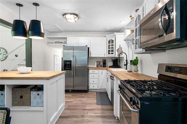 kitchen featuring stainless steel appliances, hanging light fixtures, white cabinets, and wooden counters