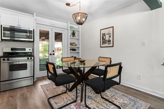 dining room featuring french doors, an inviting chandelier, built in shelves, and dark wood-type flooring