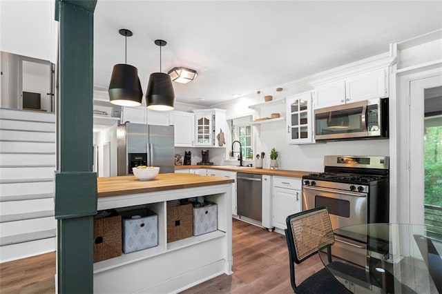 kitchen featuring wooden counters, stainless steel appliances, dark wood-type flooring, pendant lighting, and white cabinetry