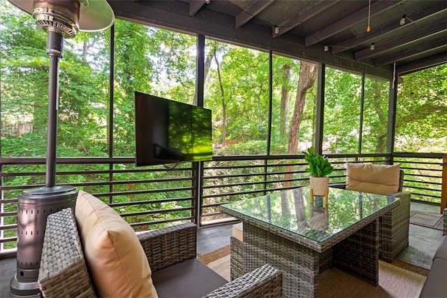 sunroom featuring beamed ceiling and a healthy amount of sunlight