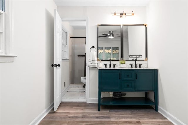 bathroom with ceiling fan, toilet, wood-type flooring, and vanity