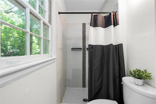 bathroom with a shower with curtain, toilet, and a healthy amount of sunlight