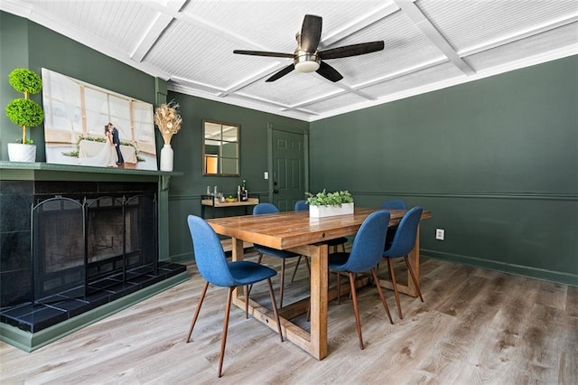 dining area featuring a tiled fireplace, ceiling fan, and hardwood / wood-style flooring