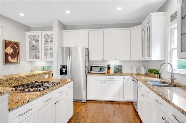 1473 Cardova Pointe, Dunwoody, GA 30338 - kitchen with stainless steel appliances, white cabinetry, light wood-style flooring, tasteful backsplash, and glass insert cabinets