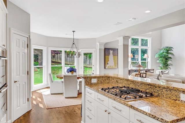 1473 Cardova Pointe, Dunwoody, GA 30338 - kitchen with stovetop with downdraft, wood finished floors, white cabinets, light stone countertops, and a chandelier