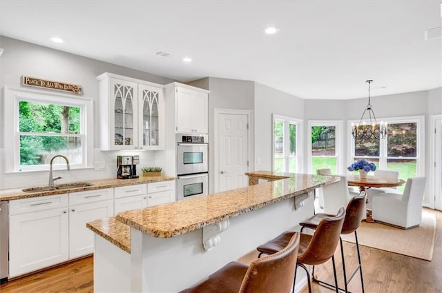 1473 Cardova Pointe, Dunwoody, GA 30338 - kitchen with appliances with stainless steel finishes, light wood-style floors, glass insert cabinets, white cabinetry, and a breakfast bar