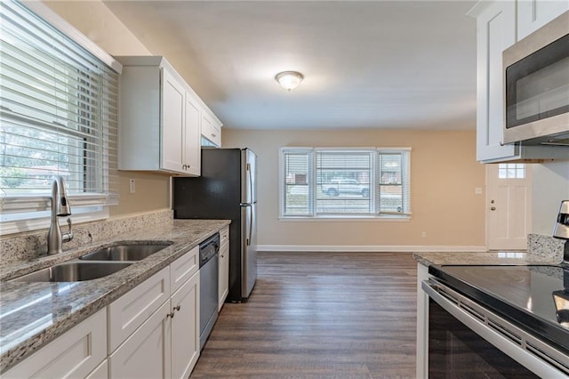 kitchen with sink, light stone counters, dark hardwood / wood-style floors, white cabinets, and appliances with stainless steel finishes