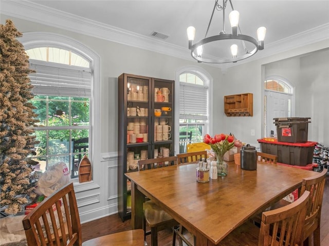 dining area with dark hardwood / wood-style flooring, an inviting chandelier, and ornamental molding