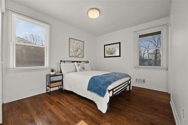 bedroom featuring visible vents, multiple windows, baseboards, and dark wood-style floors