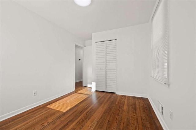 unfurnished bedroom with wood finished floors, a closet, and baseboards