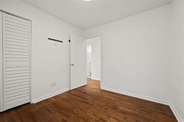 unfurnished bedroom featuring wood finished floors, baseboards, and a closet