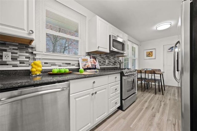 kitchen featuring light wood finished floors, appliances with stainless steel finishes, white cabinetry, and dark countertops