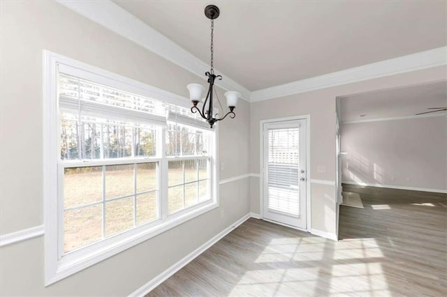 unfurnished dining area featuring hardwood / wood-style flooring, crown molding, and a notable chandelier